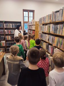 Bibliotekarka oprowadza dzieci po działach biblioteki