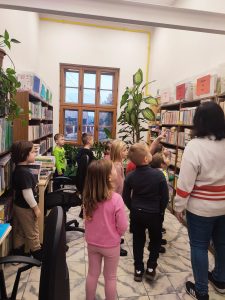 Bibliotekarka oprowadza dzieci po działach biblioteki