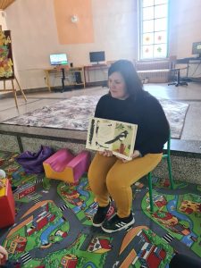 Bibliotekarka prezentuje dzieciom Mały atlas ptaków.